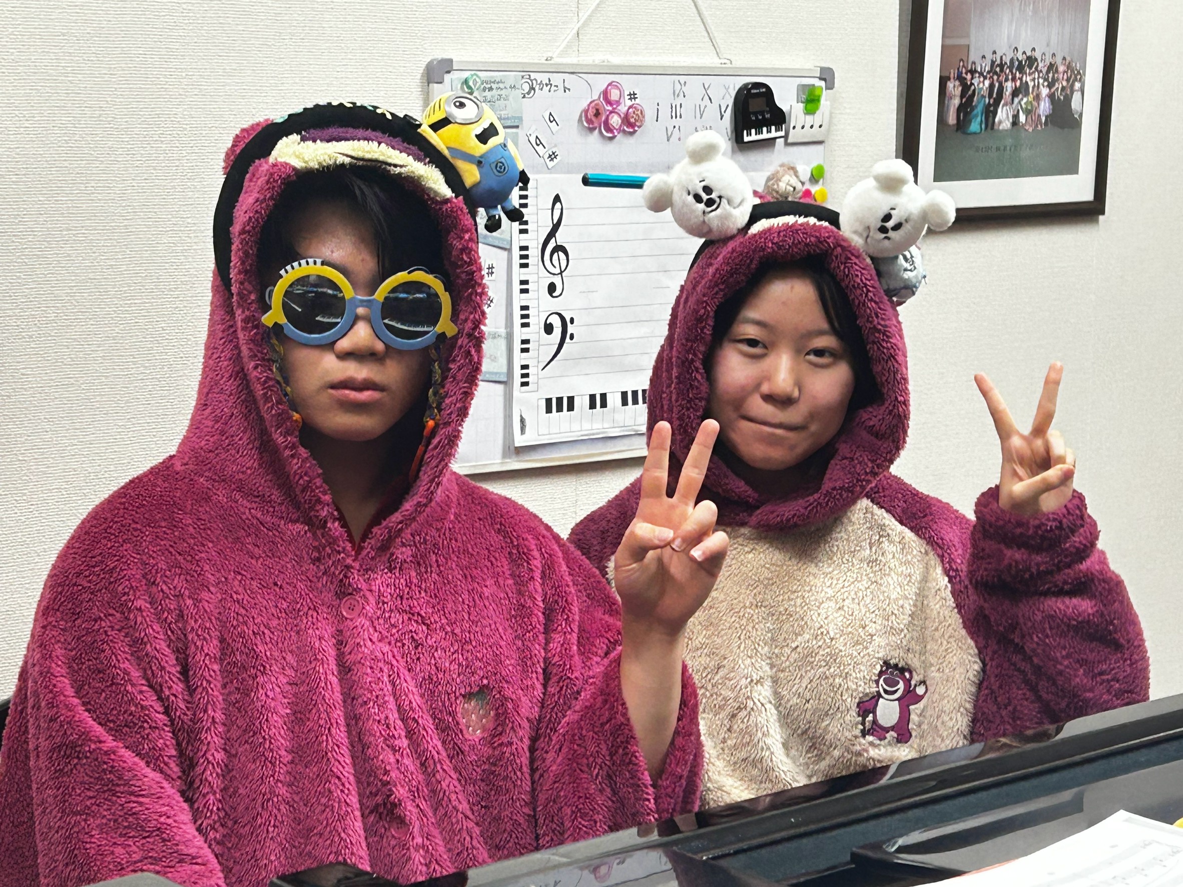 クマの衣装とサングラスでピアノの前に座る2人